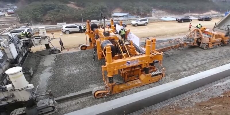 Large machinery laying and compacting concrete for road construction