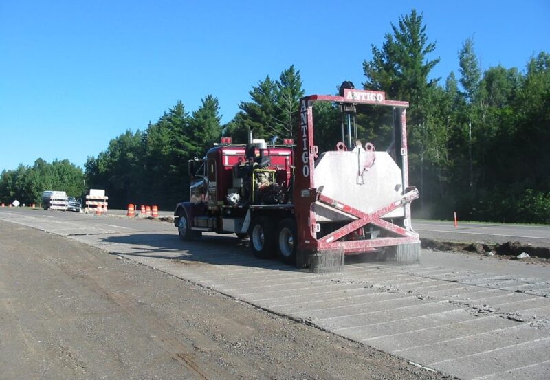 Concrete road surface being milled by heavy machinery for pavement Rehabilitation