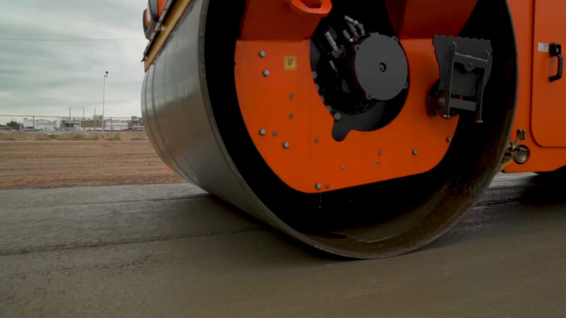 Close-up of a vibratory roller compacting freshly laid concrete pavement